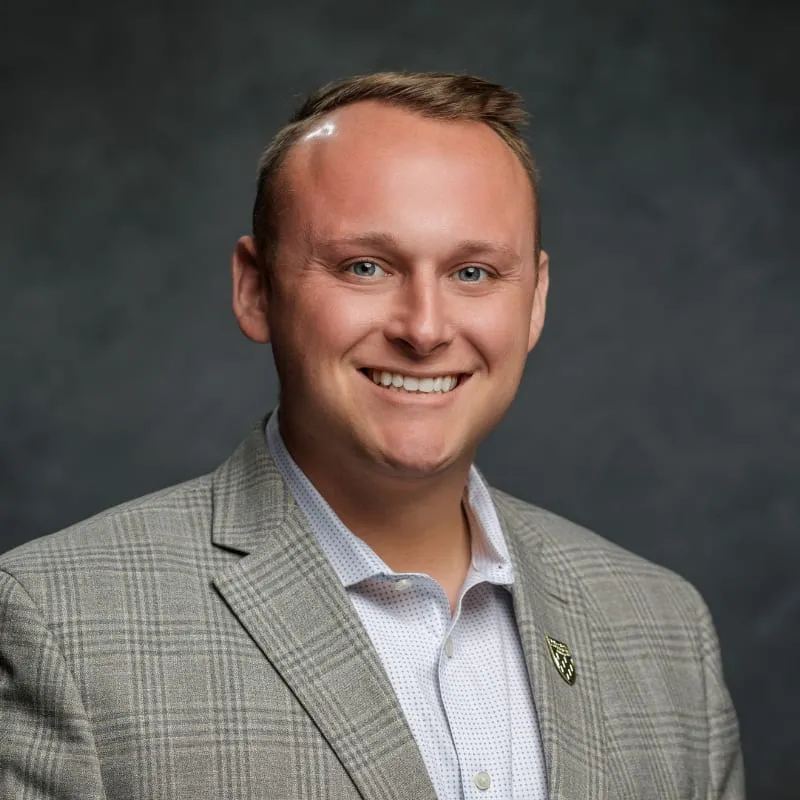 Matthew Sheldon smiling, in a grey plaid jacket